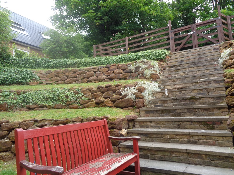Rosewood terraced rear garden with bench and hedging